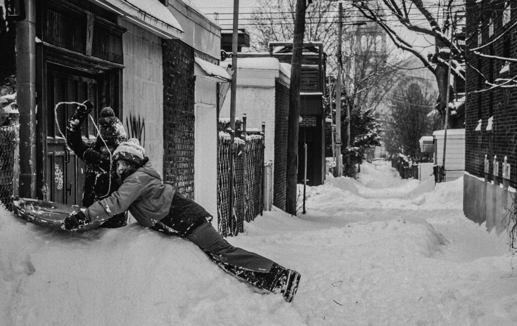 Deux enfants jouent sur un talus de neige, dans une ruelle du Quartier Villeray à Montréal. La photo a été prise en 2016.